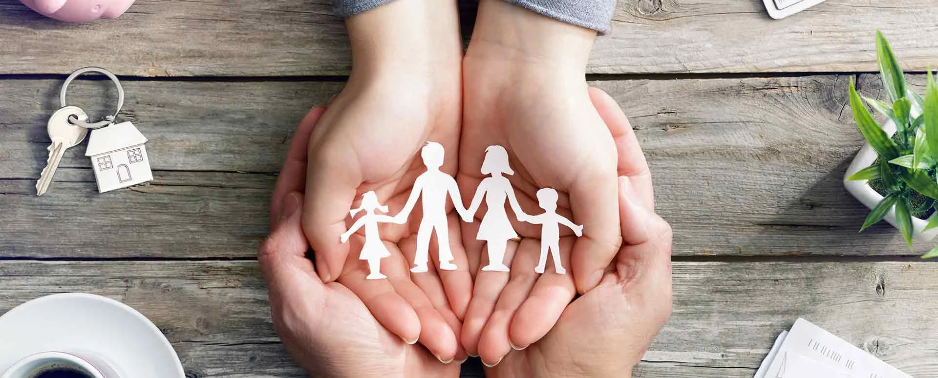 Hands gently holding paper figures of a family